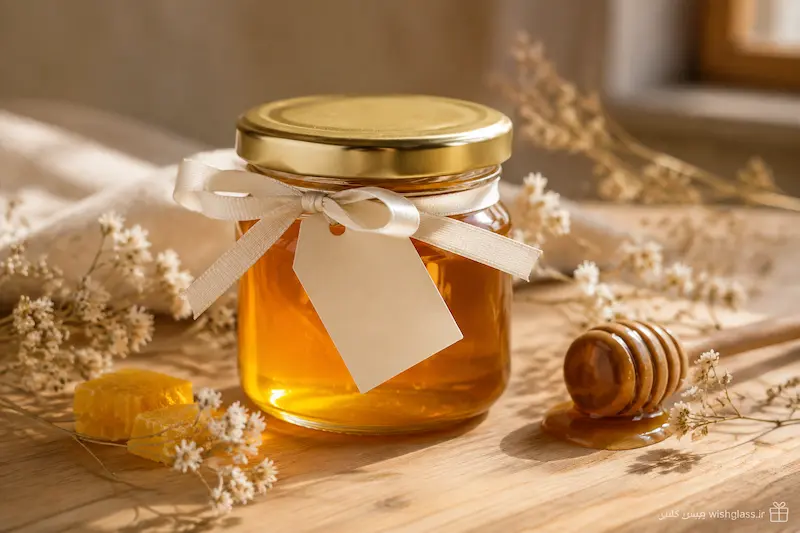 شیشه گیفت عسل کوچک با عسل طبیعی، درب فلزی طلایی و تزئین روبان برای هدیه